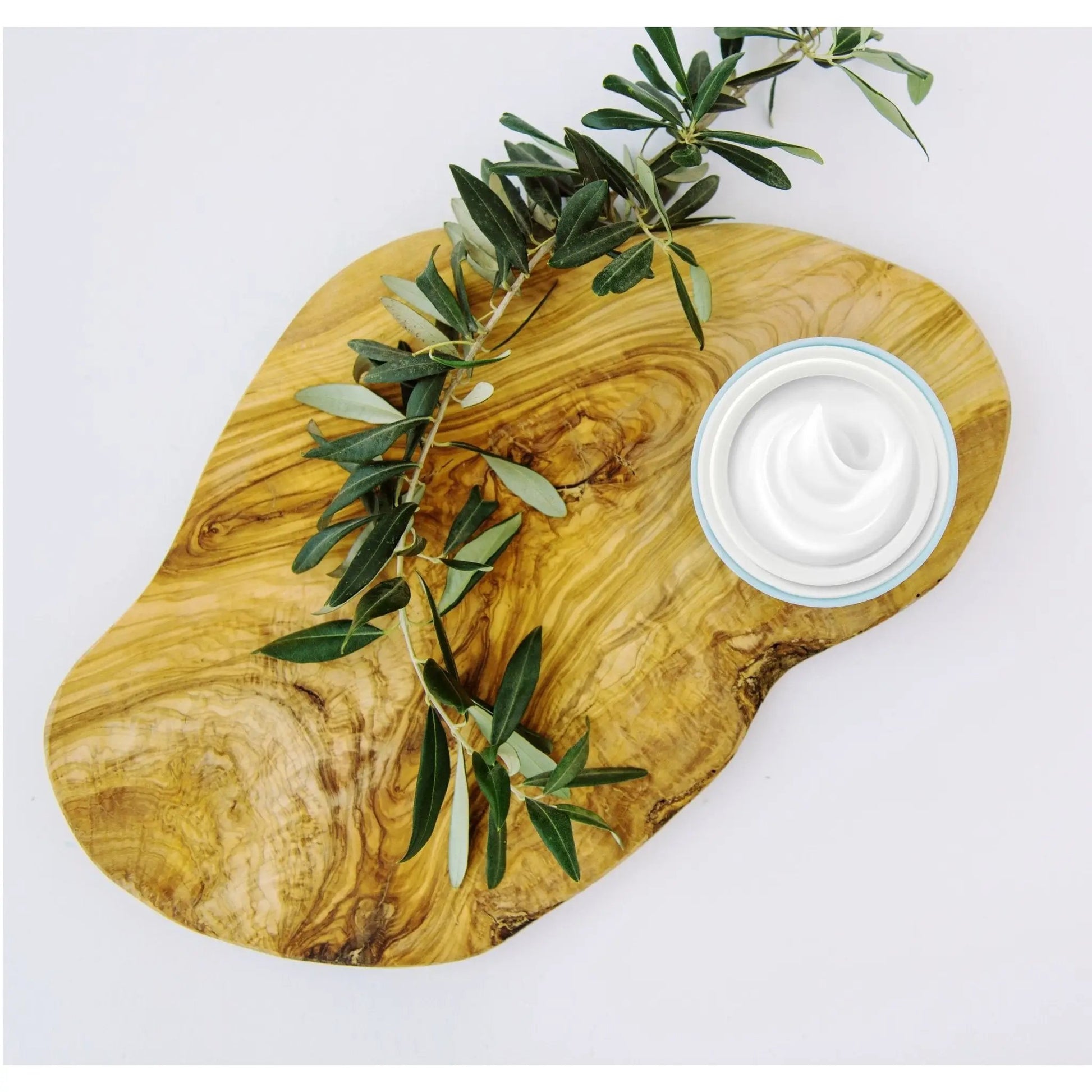 Open jar of Dead Sea Minerals Foot Cream on a wooden board with olive branches. A luxurious foot moisturizer for hydration and care.